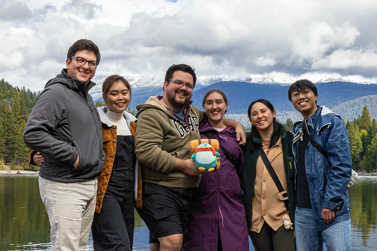 Group of six friends posing together with Pio in a scenic outdoor setting at Mount Shasta and Lake Siskiyou.